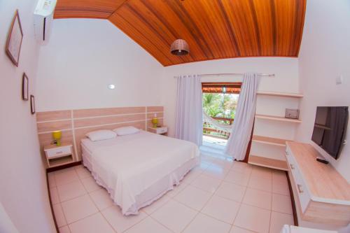 a bedroom with a white bed and a television at Recanto do Barao Pousada in Jericoacoara