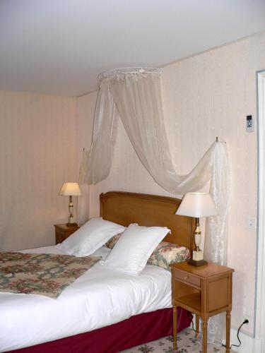 a bedroom with two beds and two tables with lamps at Chateau de la Rozelle in Cellettes