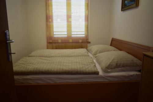 Cette chambre comprend un lit avec deux oreillers et une fenêtre. dans l'établissement Apartment Grace, à Malinska