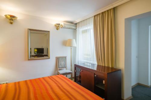 a hotel room with a bed and a desk and a mirror at Casa Sofia in Bucharest
