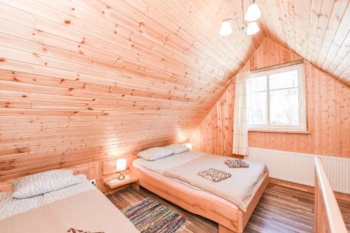 1 dormitorio con 2 camas en una pared de madera en Manto Apartamentai, en Druskininkai
