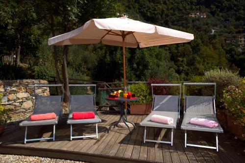 Villa Paggi Country House في Carasco: كرسيين ومظلة على سطح خشبي