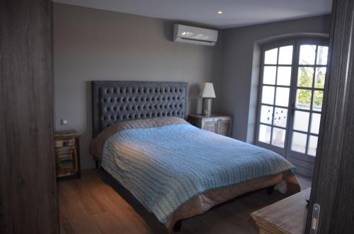 a bedroom with a bed with a blue blanket and a window at Belle maison avec piscine dans les hauteurs à Saint Raphael in Saint-Raphaël