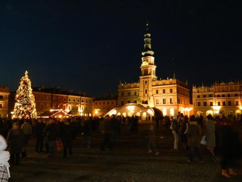 a group of people standing in front of a building with a christmas tree at Hotel Carskie Koszary in Zamość