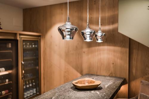 a kitchen with a table with three pendant lights at Hotel Förstlerhof in Postal