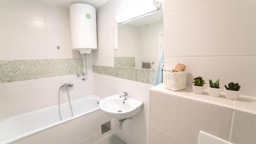 a white bathroom with a sink and a bath tub at Novel Inn in Belgrade