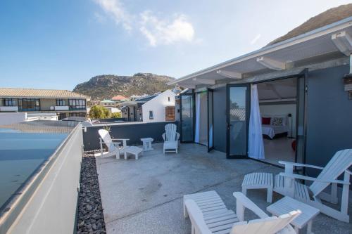 a house with a patio with chairs and a pool at Rosmead Apartment in Kalk Bay