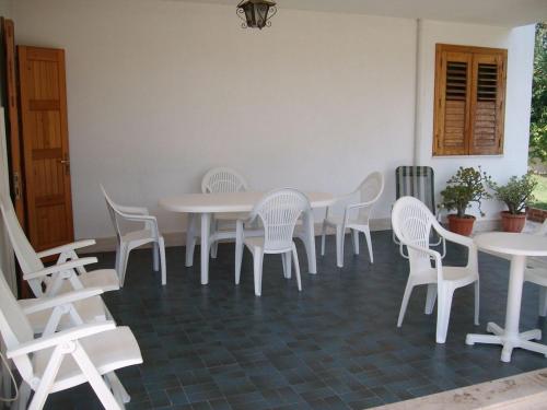 una sala da pranzo con tavoli e sedie bianchi di Appartamento in villa a Fontane Bianche a Fontane Bianche