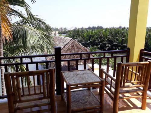 two chairs and a table on a balcony with palm trees at Lakeview Villa Homestay in Hoi An