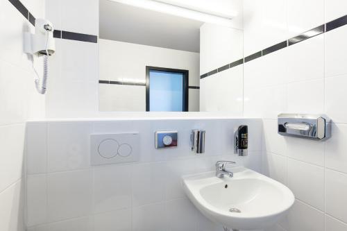 a white bathroom with a sink and a mirror at a&o Prague Rhea in Prague