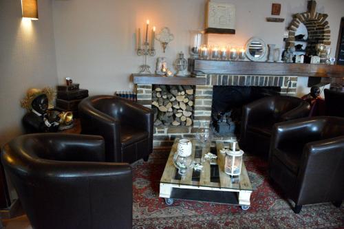 a living room with leather chairs and a fireplace at Auberge Le Relais in Corbion