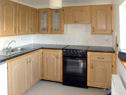 eine Küche mit Holzschränken und einem schwarzen Gerät in der Unterkunft 2 Clancy Cottages in Kilkieran