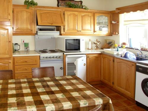 a kitchen with wooden cabinets and a table in it at Droumatouk Cottage in Kenmare