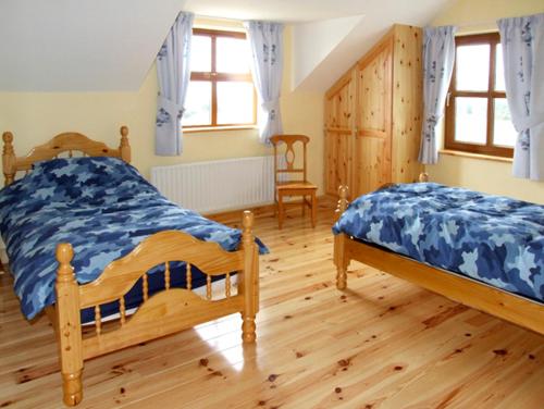 a bedroom with two beds and a wooden floor at Ardagh North in Barloge