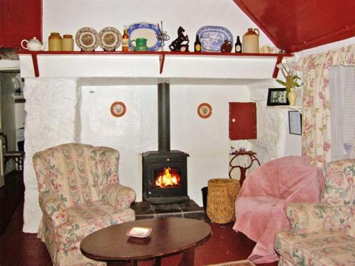 ein Wohnzimmer mit einem Kamin, einem Tisch und Stühlen in der Unterkunft Carthy's Cottage in Kilbrien