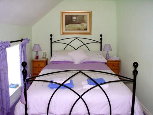 a bedroom with a large bed with purple sheets at Fehanaugh Cottage in Atadav Bridge