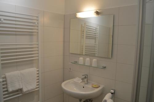 a white bathroom with a sink and a mirror at Dünenmeer in Juist