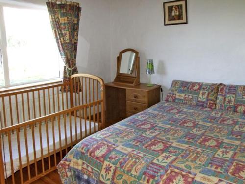 a bedroom with a bed and a crib and a mirror at Delia's Cottage in Ballinrobe