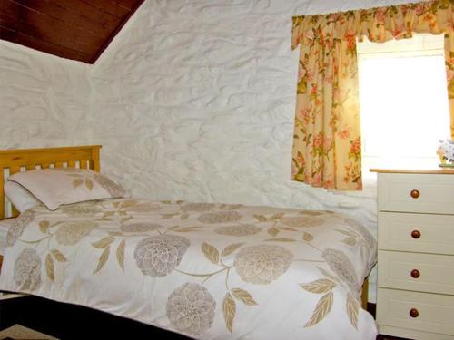 ein Schlafzimmer mit einem Bett, einer Kommode und einem Fenster in der Unterkunft Carthy's Cottage in Kilbrien