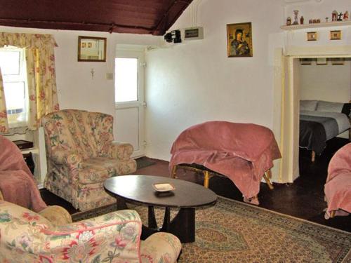ein Wohnzimmer mit einem Sofa, Stühlen und einem Tisch in der Unterkunft Carthy's Cottage in Kilbrien