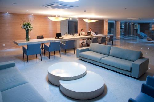 a lobby with a long table and blue couches at Hotel Brisa Praia Pajuçara in Maceió