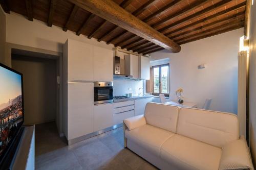a living room with a white couch and a kitchen at Rocca Palazzaccio in Impruneta