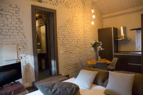 a living room with a couch and a brick wall at La Canonica - charming self-catering apartments in Nizza Monferrato in Nizza Monferrato