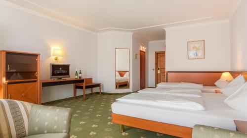 a hotel room with four beds and a television at Alpenland St Johann in Sankt Johann im Pongau
