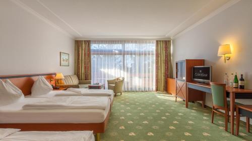 a hotel room with two beds and a desk at Alpenland St Johann in Sankt Johann im Pongau