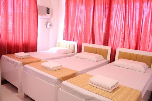 three beds in a room with red curtains at Butuan Grand Palace Hotel Annex in Butuan