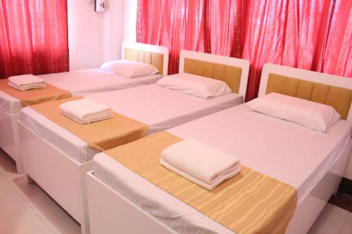 three beds in a room with red curtains at Butuan Grand Palace Hotel Annex in Butuan