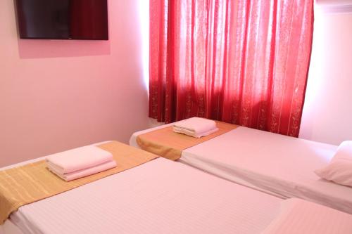 two beds in a room with a red curtain at Butuan Grand Palace Hotel Annex in Butuan