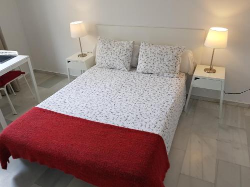 una camera con un letto con una coperta rossa e due lampade di Fan Flat Eugenio a Málaga