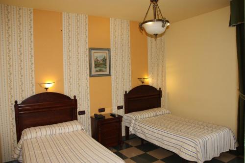 2 camas en una habitación con paredes amarillas en Hotel Frijon, en Aceuchal