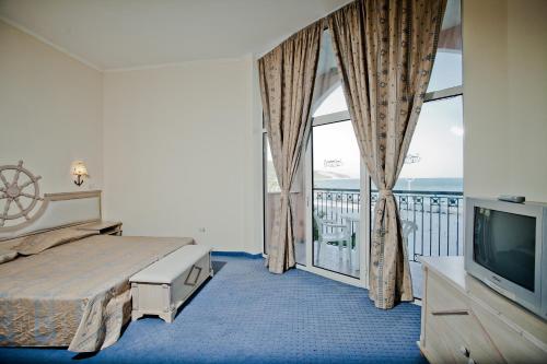 a bedroom with a bed and a tv and a balcony at Royal Park Hotel - All Inclusive in Elenite