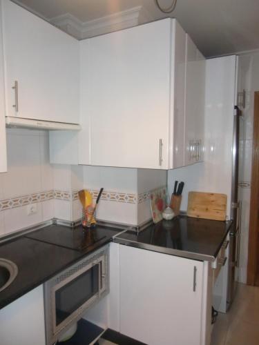 a kitchen with white cabinets and a black counter top at Apartamento DH in Zamora