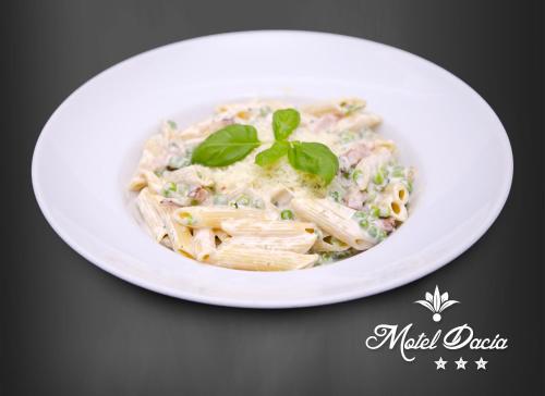 a white plate of pasta with basil on top at Motel Dacia in Sebeş