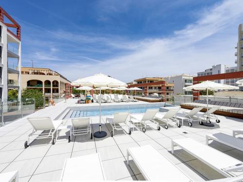 uma piscina com cadeiras e guarda-sóis num pátio em Kyrat Amarac Suites em Cala Millor