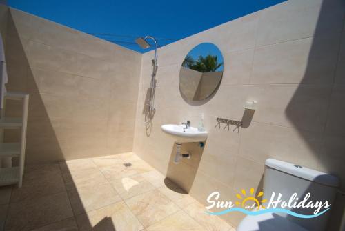 a bathroom with a sink and a mirror and a toilet at Villa Oasis in El Vendrell