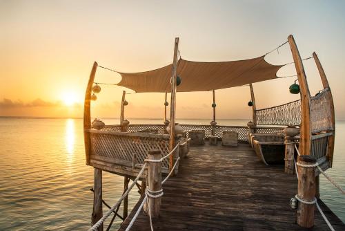 a dock with two boats on the water at sunset at Essque Zalu Zanzibar in Nungwi