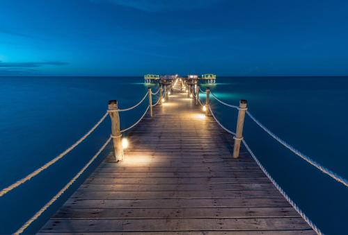 a pier with lights on the water at night at Essque Zalu Zanzibar in Nungwi