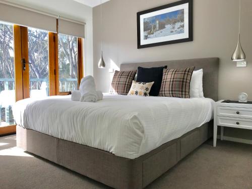 a bedroom with a large bed with white sheets and pillows at Apres in Dinner Plain