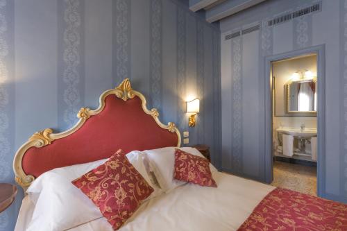 a bedroom with a bed with a red headboard and a sink at Hotel Tiziano in Venice