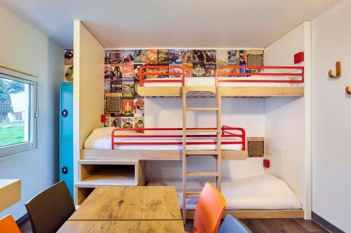 Cette chambre comprend des lits superposés, une table et des chaises. dans l'établissement hotelF1 Chartres, à Le Coudray