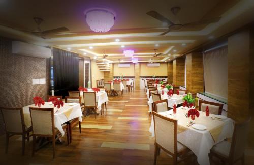 a restaurant with white tables and chairs and red flowers at Hotel City Palace in Jodhpur