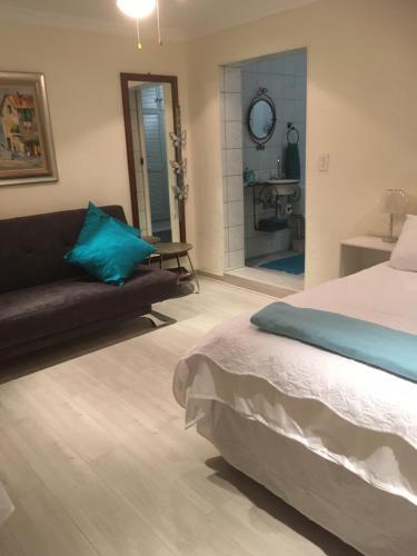 a bedroom with a bed and a couch and a bathroom at Sunninghill Sojourn in Kyalami