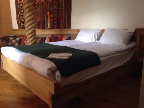 Una cama con sábanas blancas y una manta verde. en Craftsman's Home, en Tiflis