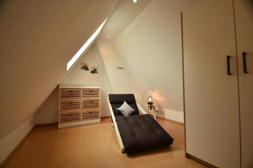 a room with a black chair in a attic at Hotel Nige Hus in Insel Neuwerk