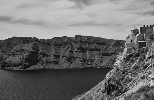 a castle on a cliff next to a body of water at Helianthus Dream Homes in Oia