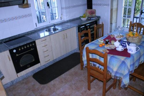 a kitchen with a table and chairs and a sink at Casa rural agro da moa in As Mirans